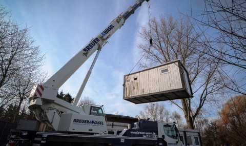 Bei der Translozierung hebt ein Krank den Container hoch.